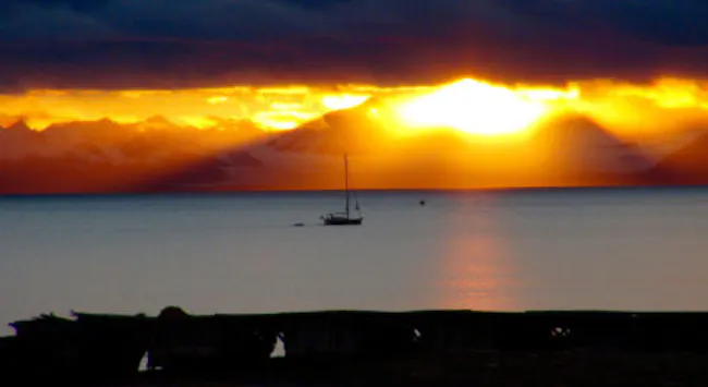 Solnedgang over hav med seilbåt