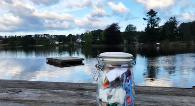 Søppel samlet i Norgesglass, plassert utendørs på en lys sommerkveld.